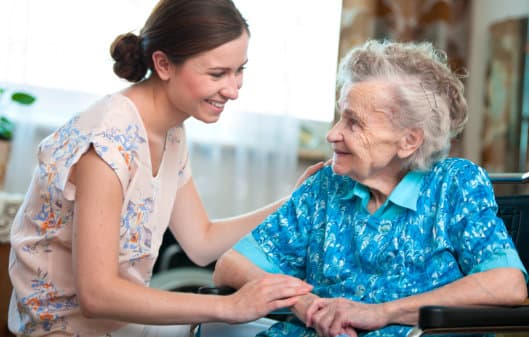 caregiver and elderly woman smiling to each other
